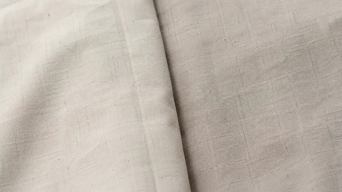 Two lengths of the same plain cloth side by side under even light, one very slightly deeper in colour than the other.